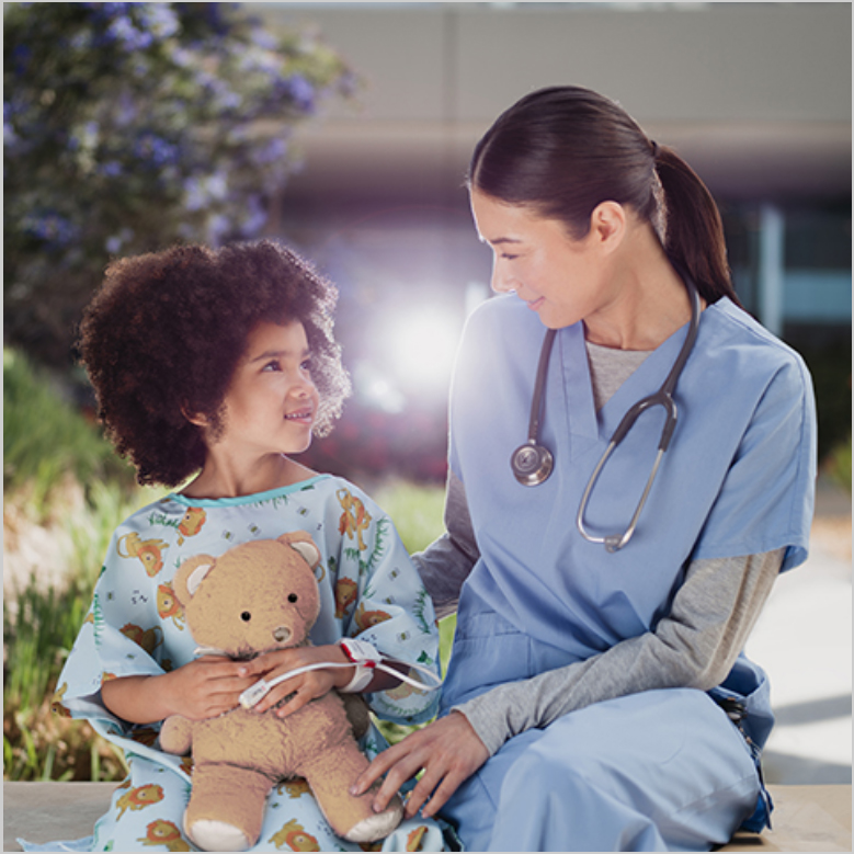 Clinician with a stethoscope sitting outdoors with a child holding a teddy bear and wearing a Masimo sensor. 